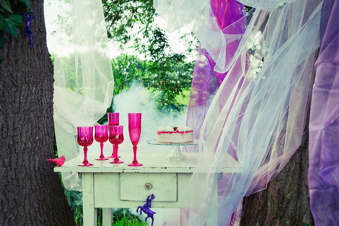 Strawberry cake on a white table between two trees