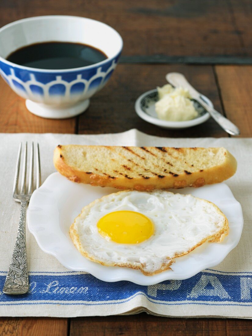 Frühstück mit Spiegelei, Toastbrot und einer Schale Kaffee