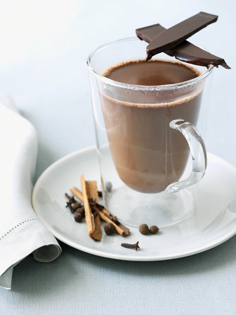 Glass Mug of Hot Chocolate with a Piece of Dark Chocolate and Spices