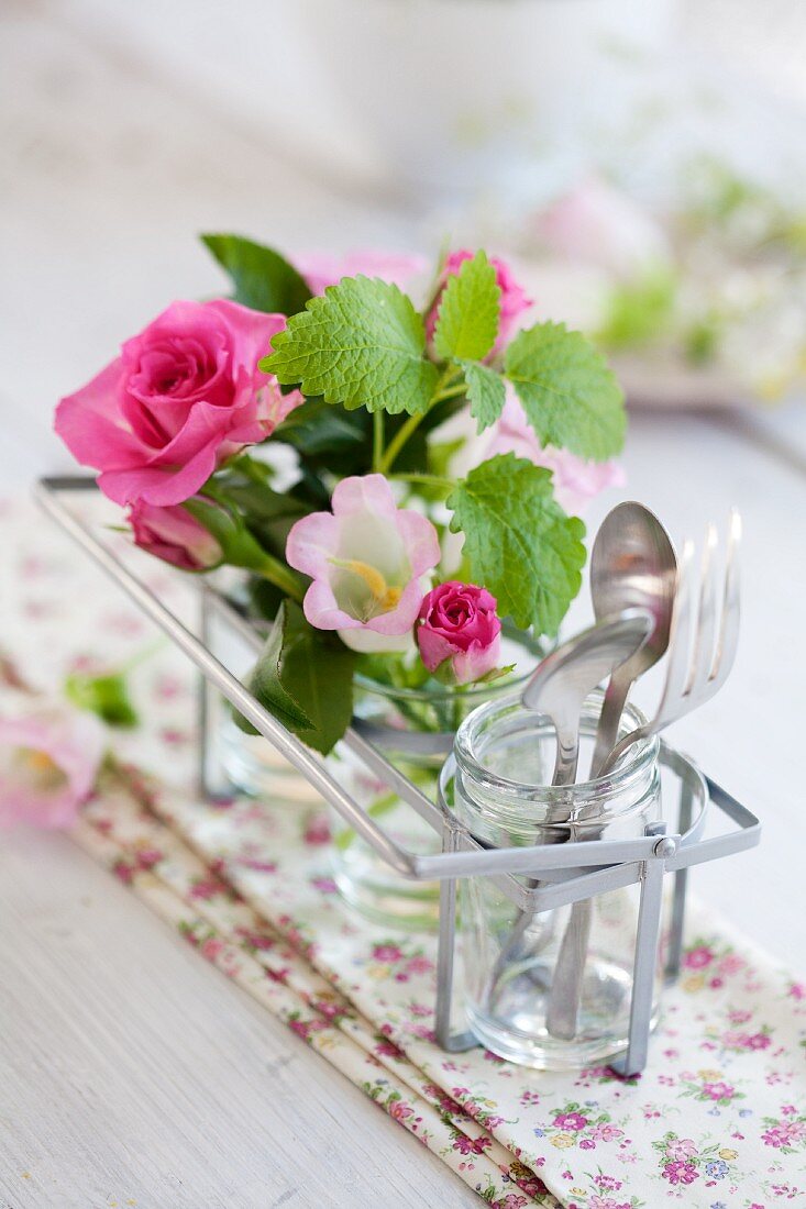 Table decoration with pink roses, bell flowers and lemon balm