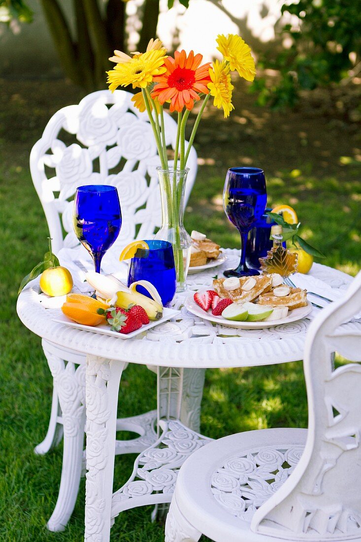 Gedeckter Frühstückstisch mit blauen Gläsern und Tellern mit frisch gebackenen Waffeln