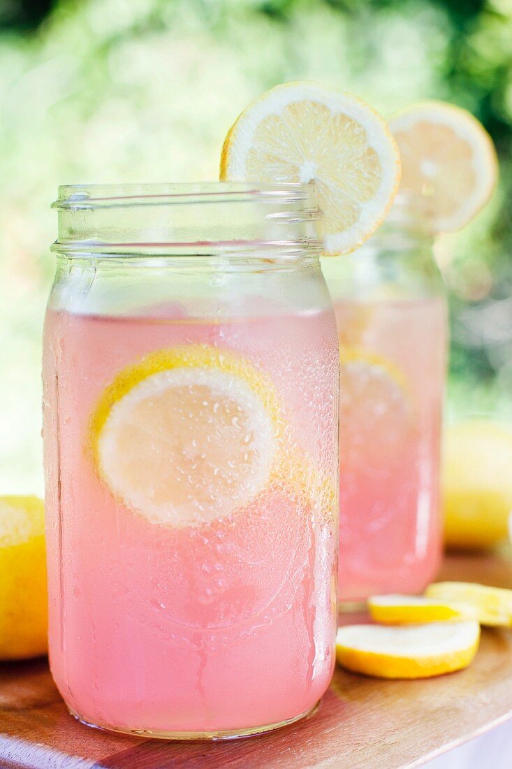 Pinkfarbene Limonade in Schraubgläsern mit Zitronenscheiben