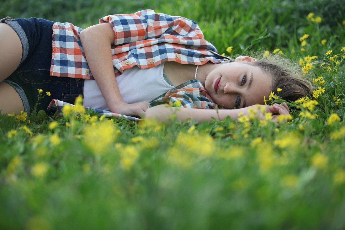 Mädchen liegt in Blumenwiese