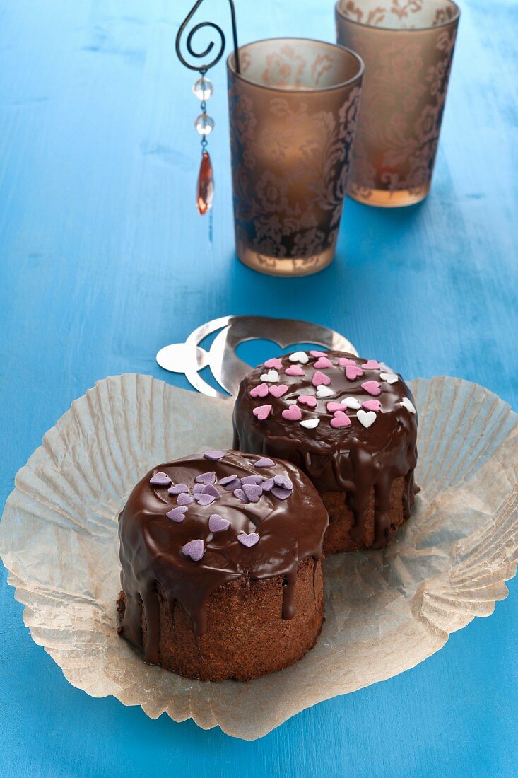 Mini chocolate cakes decorated with sugar hearts on a blue wooden table