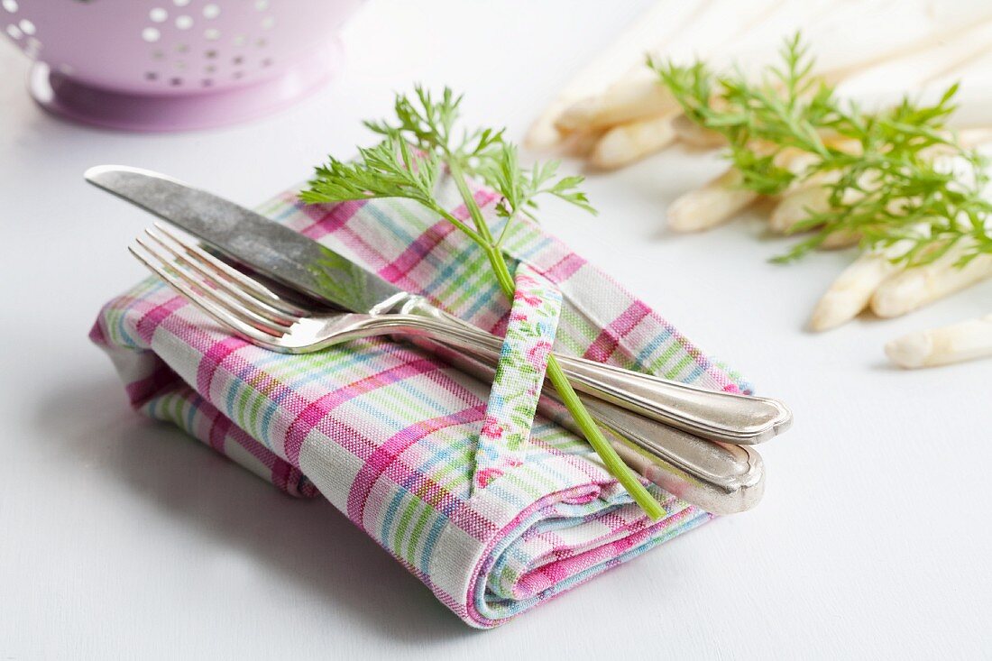 Gedeck mit Karottengrün, im Hintergrund weisser Spargel