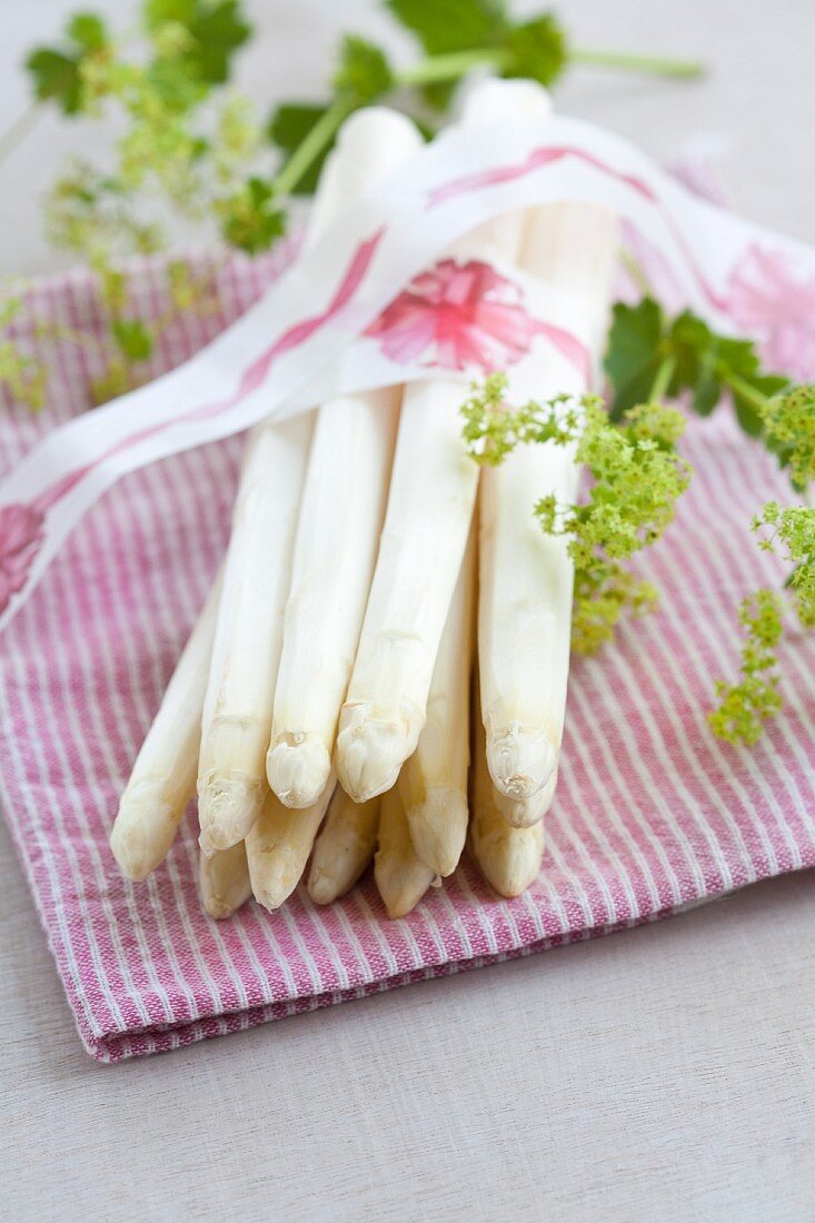 A bunch of white asparagus with a decorative ribbon and lady's mantle