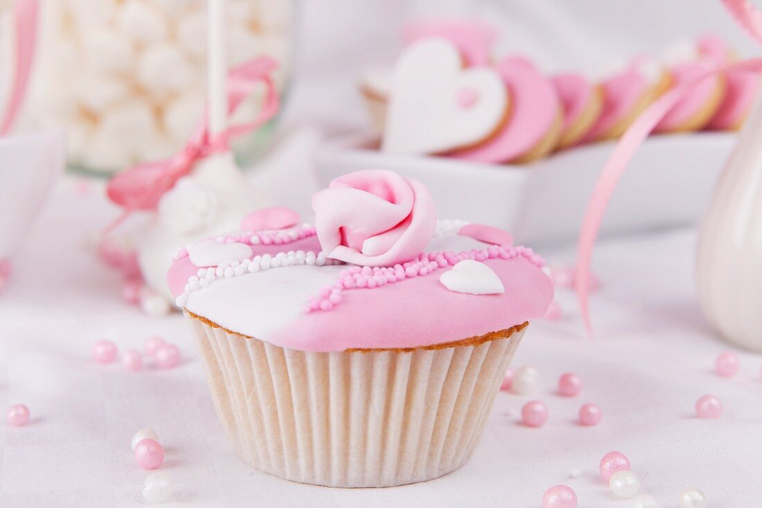 Cupcake mit rosa und weisser Glasur, Zuckerrose und Zuckerperlen