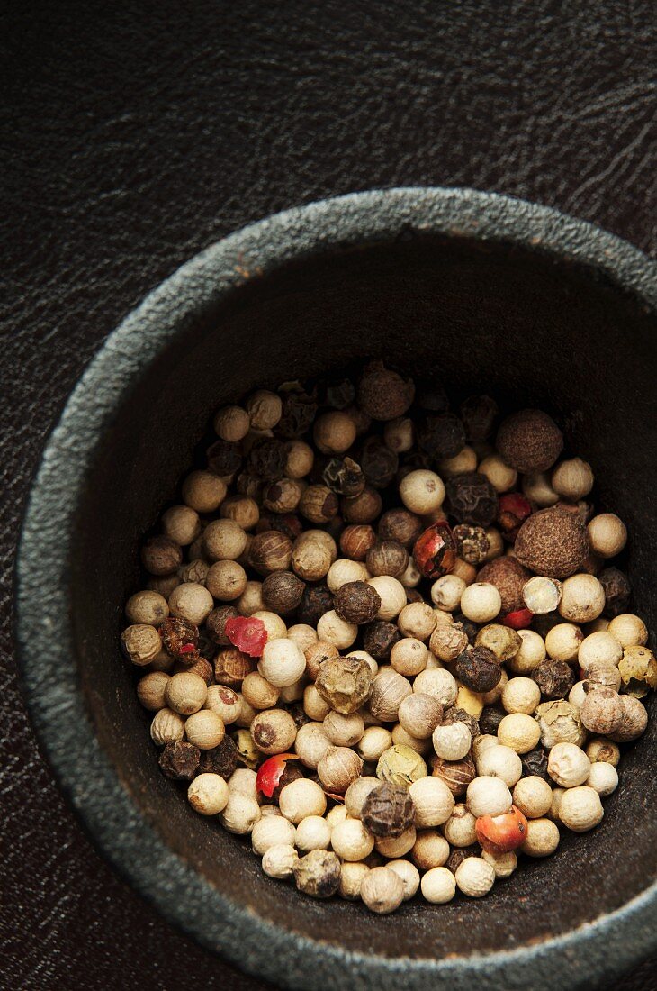 Colourful peppercorns in a metal mortar