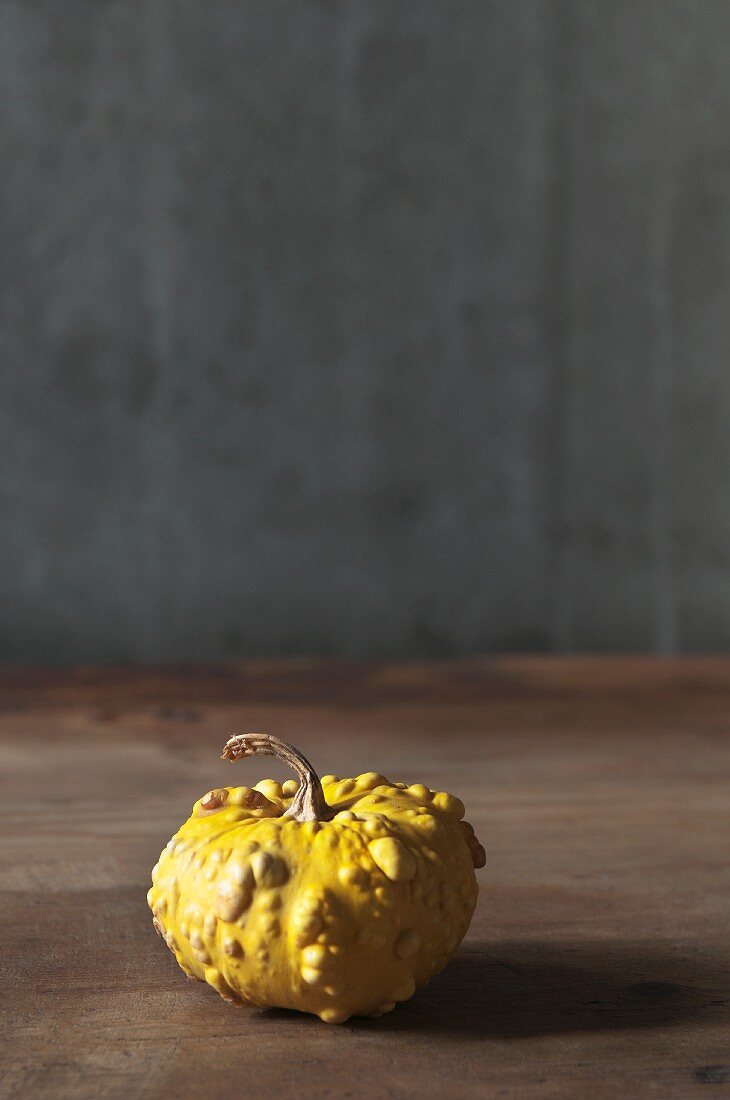 An ornamental yellow squash on a wooden table