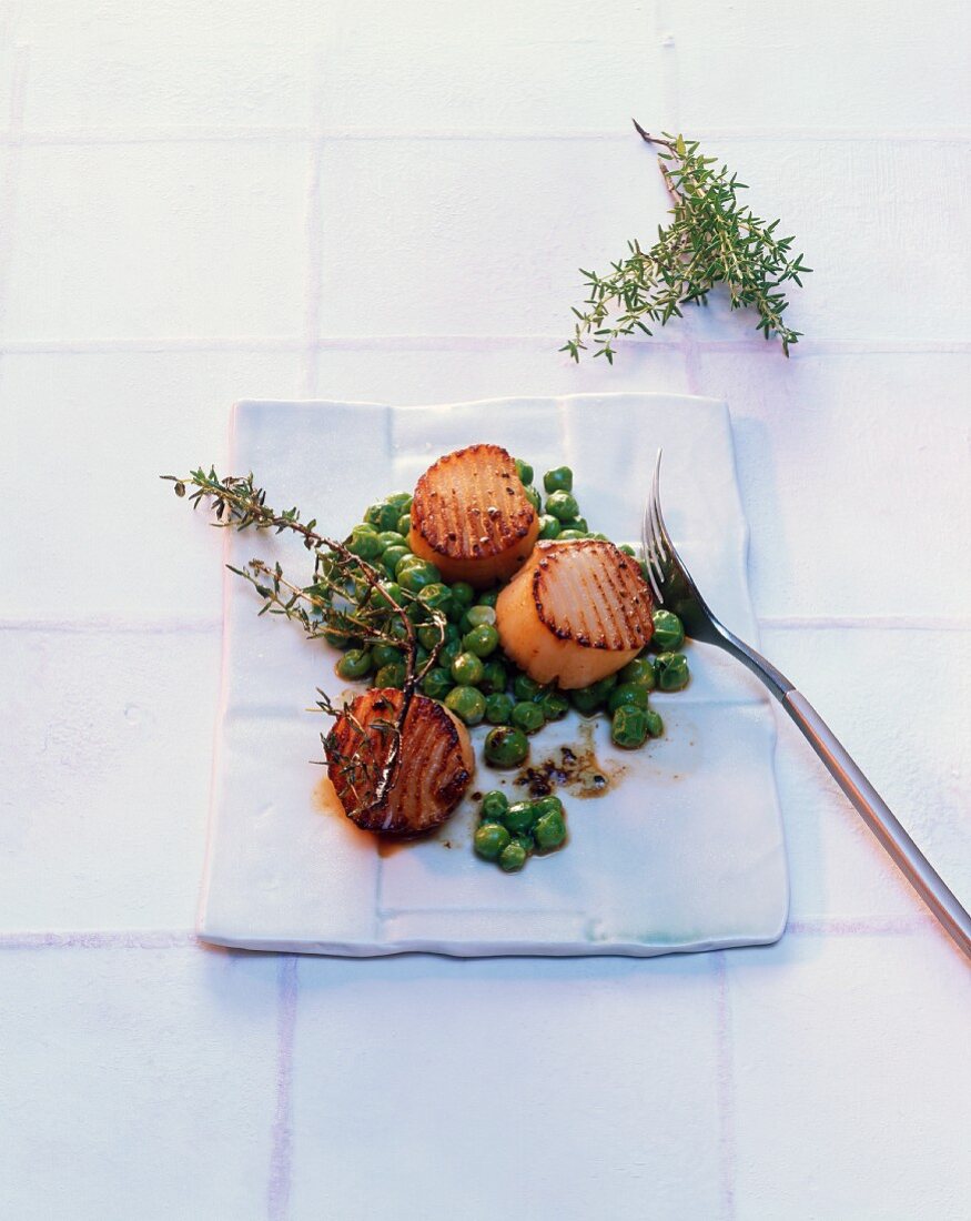 Scallops with peas and thyme cooked in a frying pan