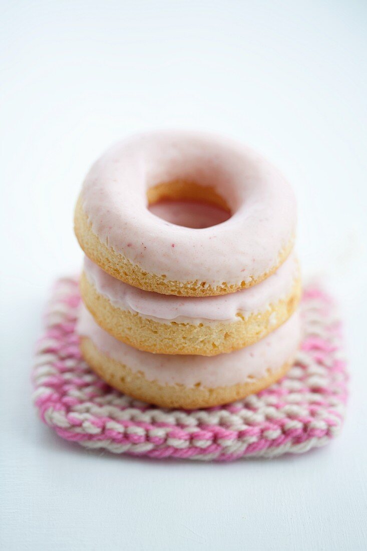Doughnuts mit rosa Zuckerguss auf Häkeldeckchen