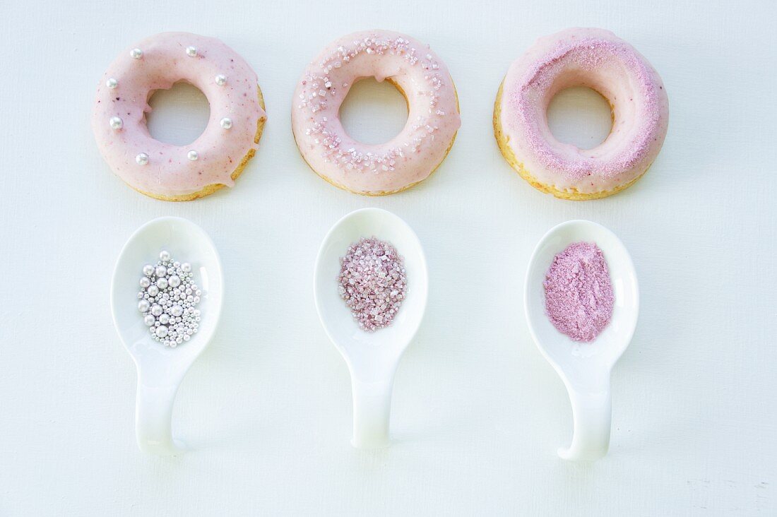 Doughnuts mit rosa Zuckerguss, Zuckerstreuseln und Zuckerperlen