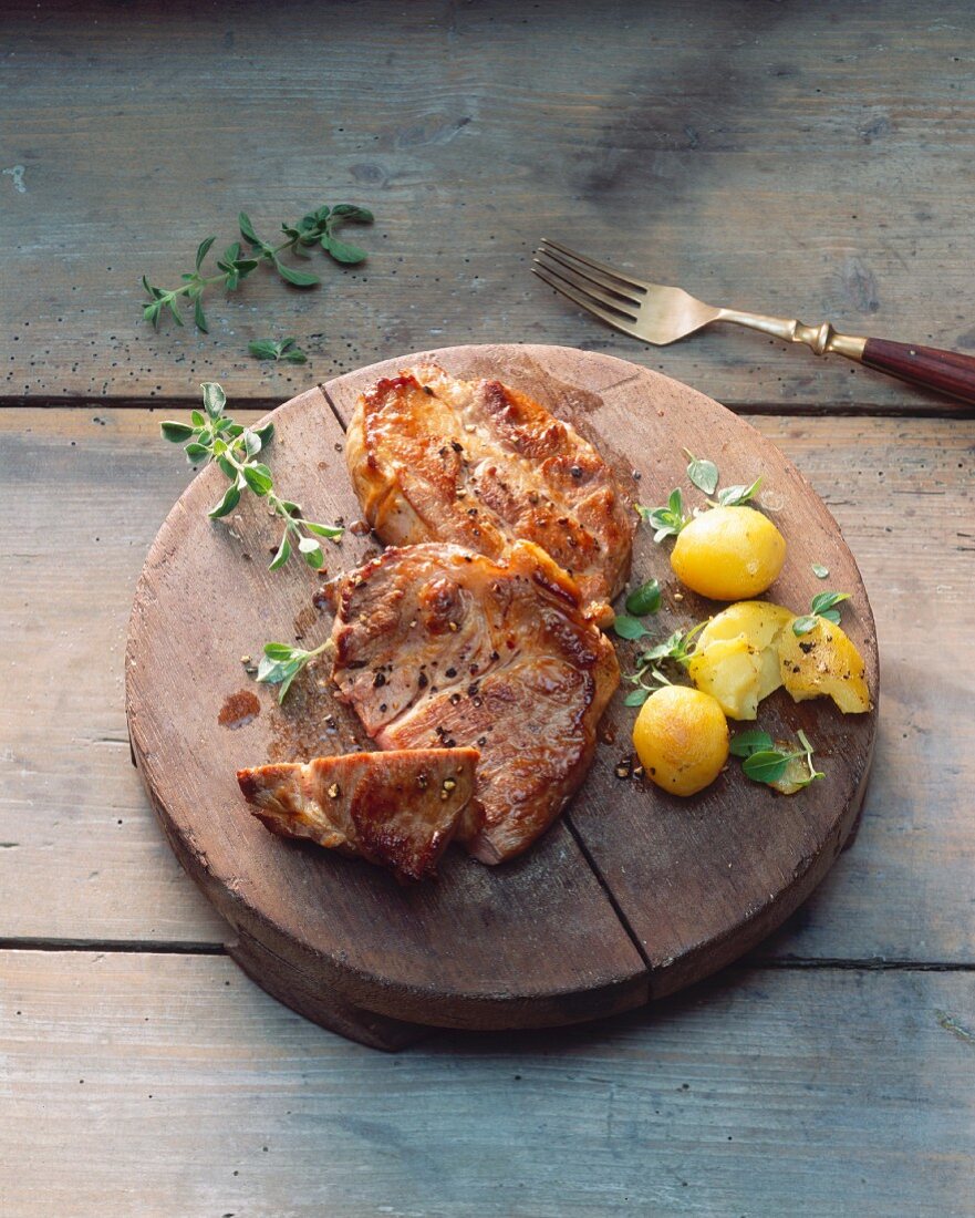 Pork steaks with potatoes on a wooden board