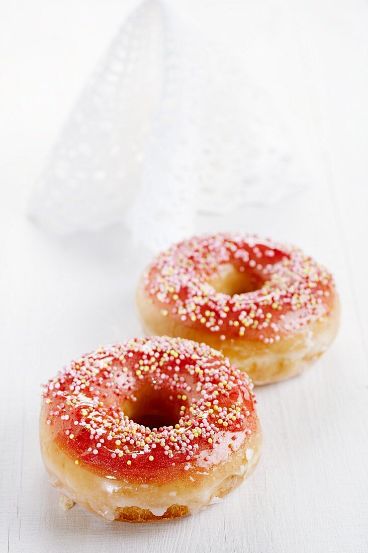 Zwei Doughnuts mit roter Glasur und Zuckerperlen