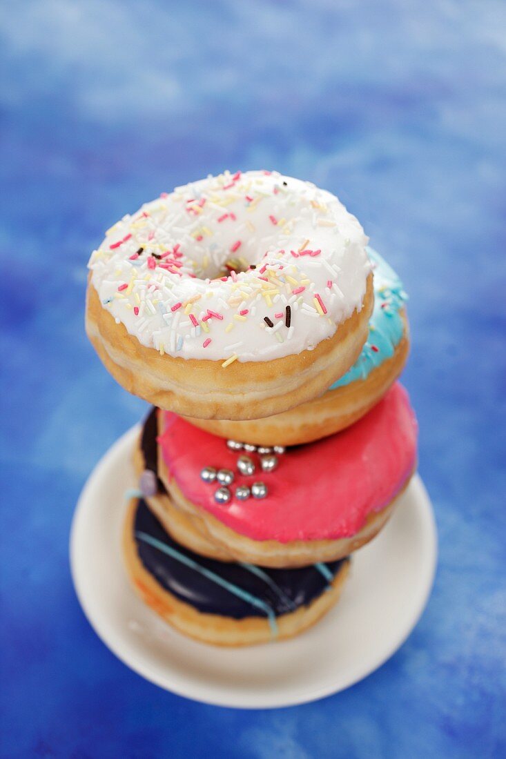 Four doughnuts with colourful glaze and sugar sprinkles