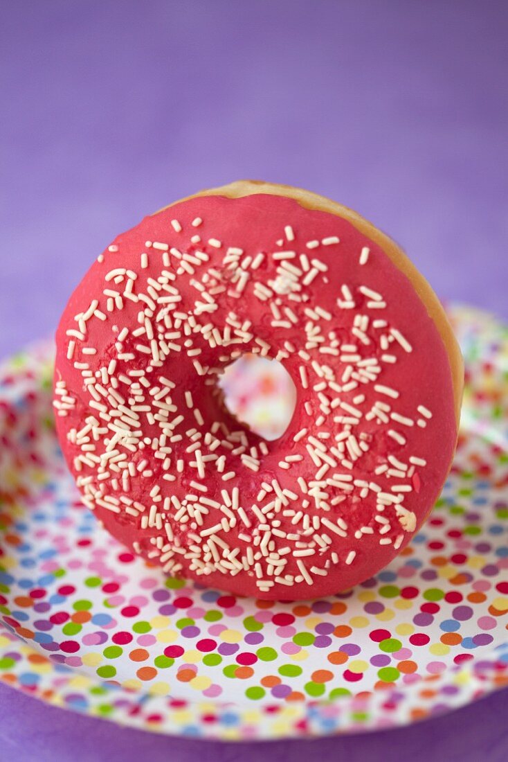 A doughnut with raspberry glaze and sugar sprinkles