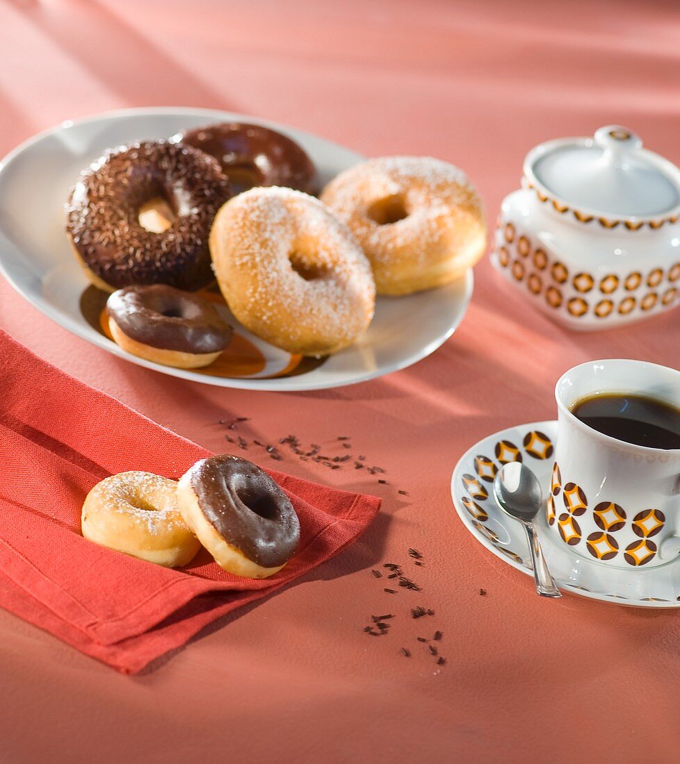 Doughnuts with sugar and chocolate glaze and a cup of coffee