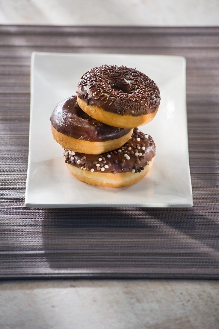 Three doughnuts with chocolate glaze and chocolate sprinkles