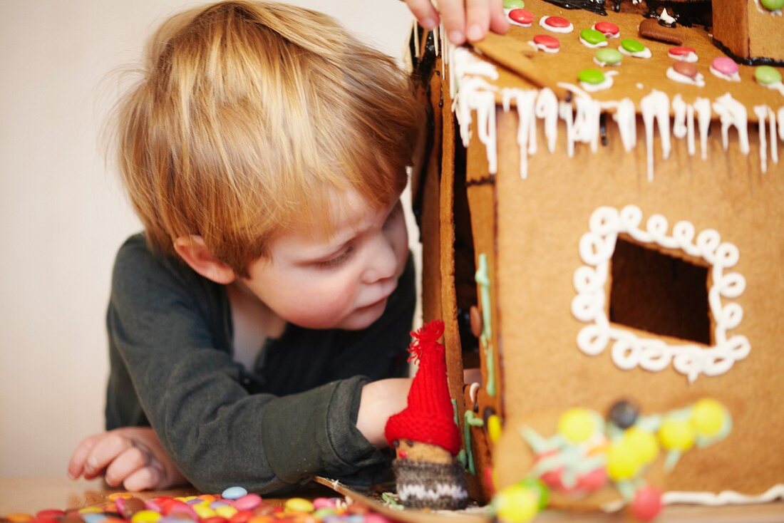 A boy decorating a gingerbread house