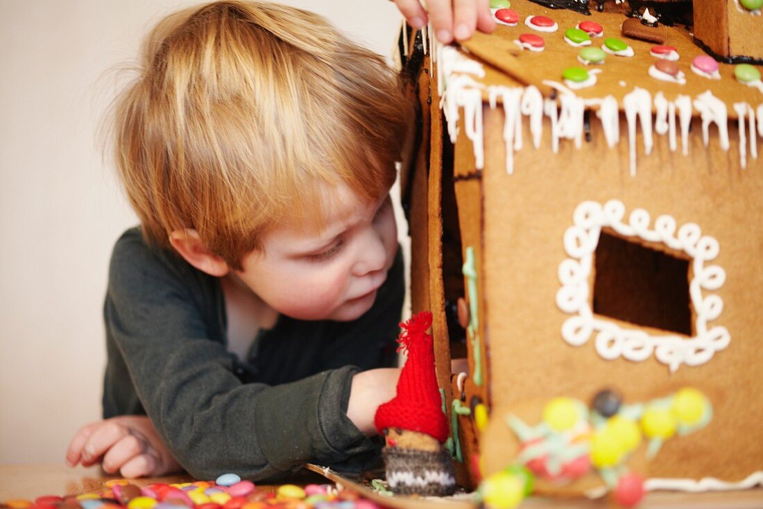 Kleiner Junge dekoriert Lebkuchenhaus