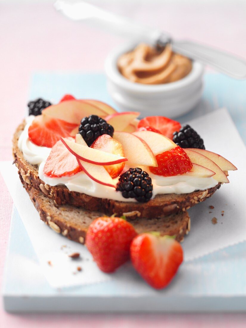 A slice of bread topped with cream cheese and fruit