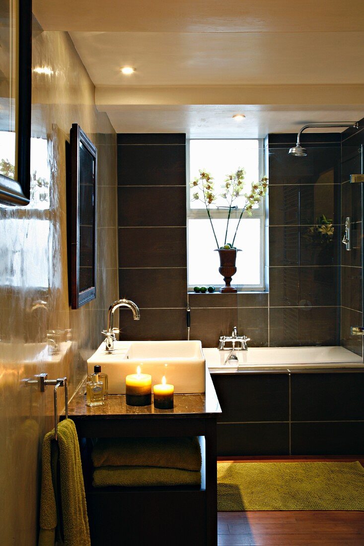 Polished walls and black tiles in bathroom with bathtub and sink