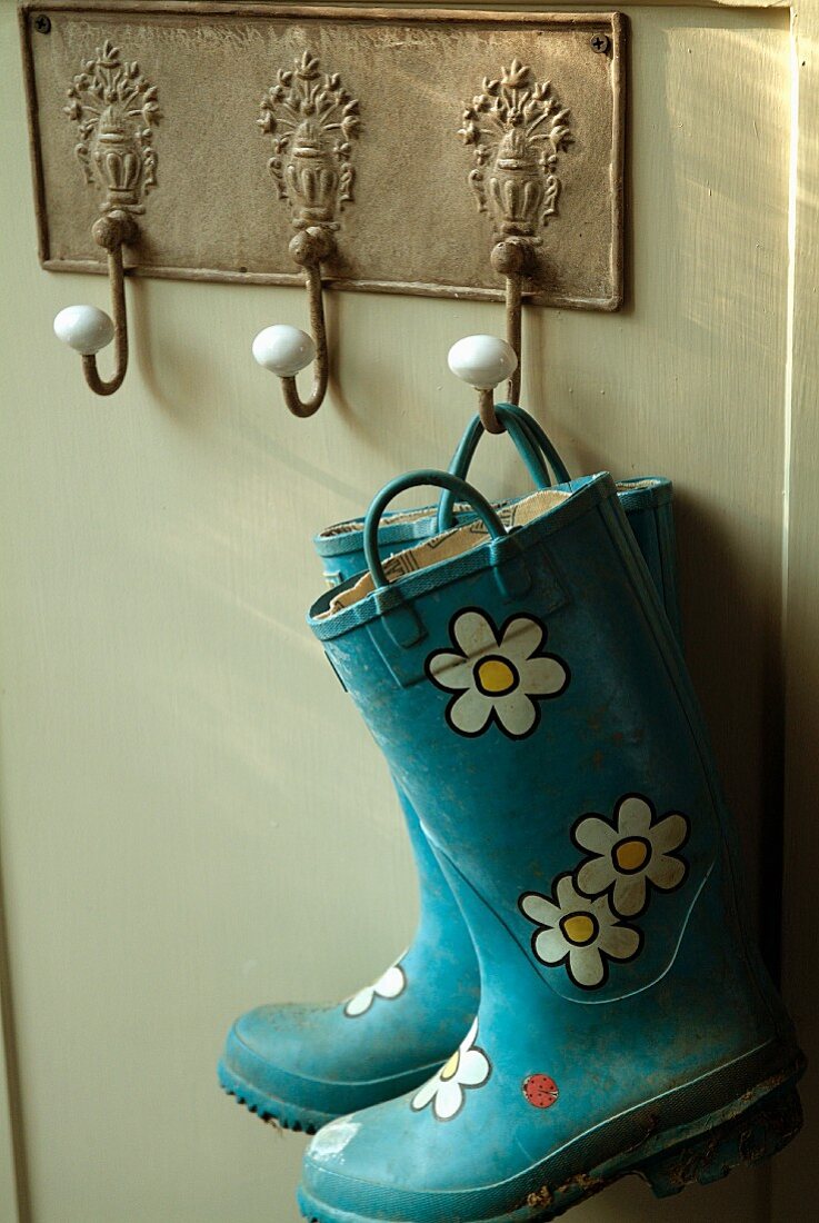Blue wellingtons with flower pattern hanging from nostalgic metal plate with coat pegs