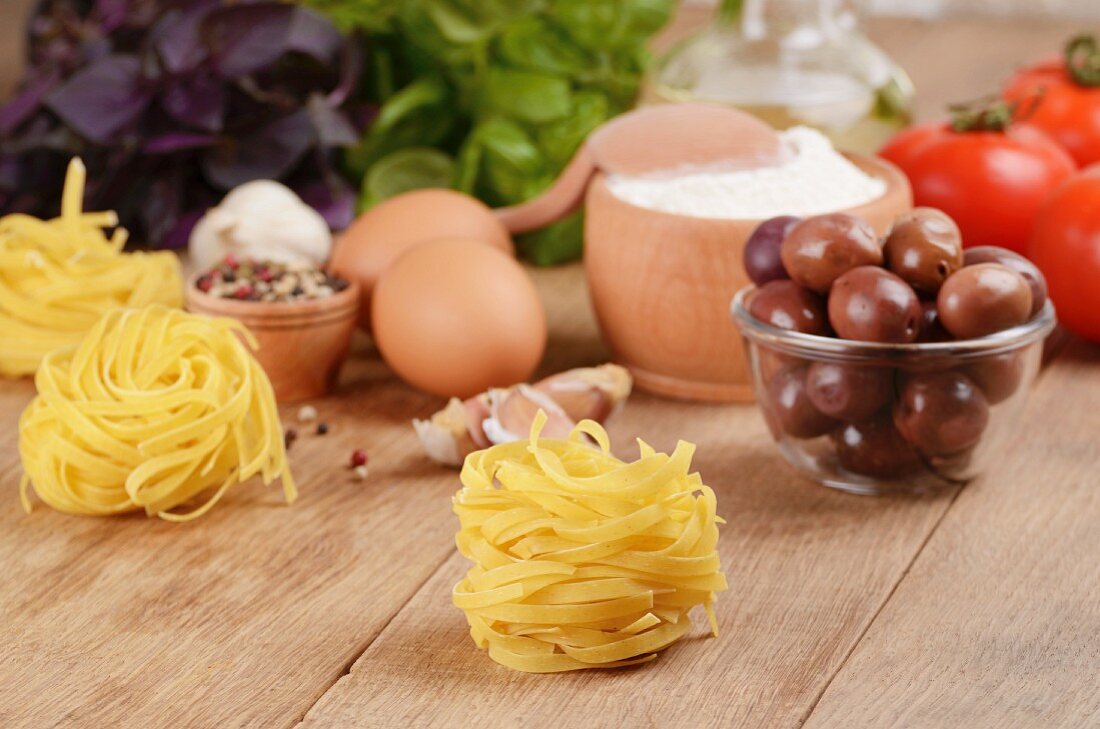 Tagliatelle, Eier, Mehl, Oliven, Tomaten und Basilikum