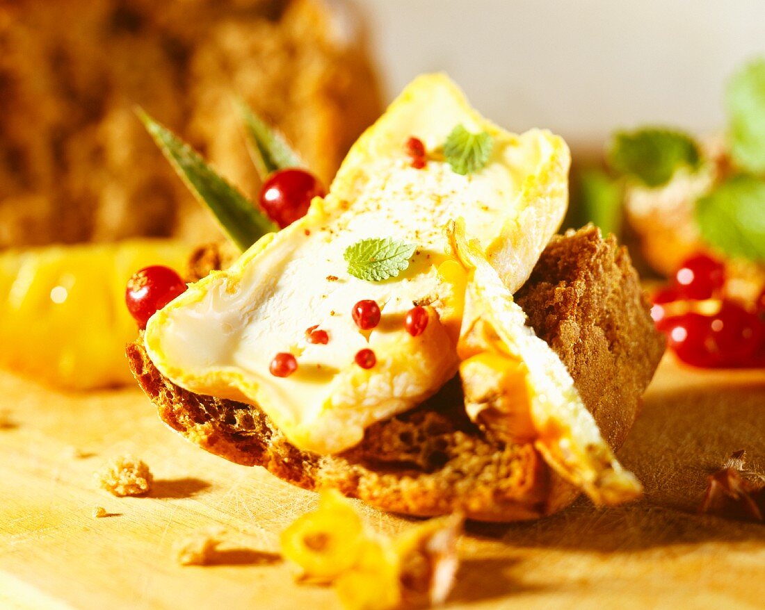 A slice of bread with soft cheese and pink pepper