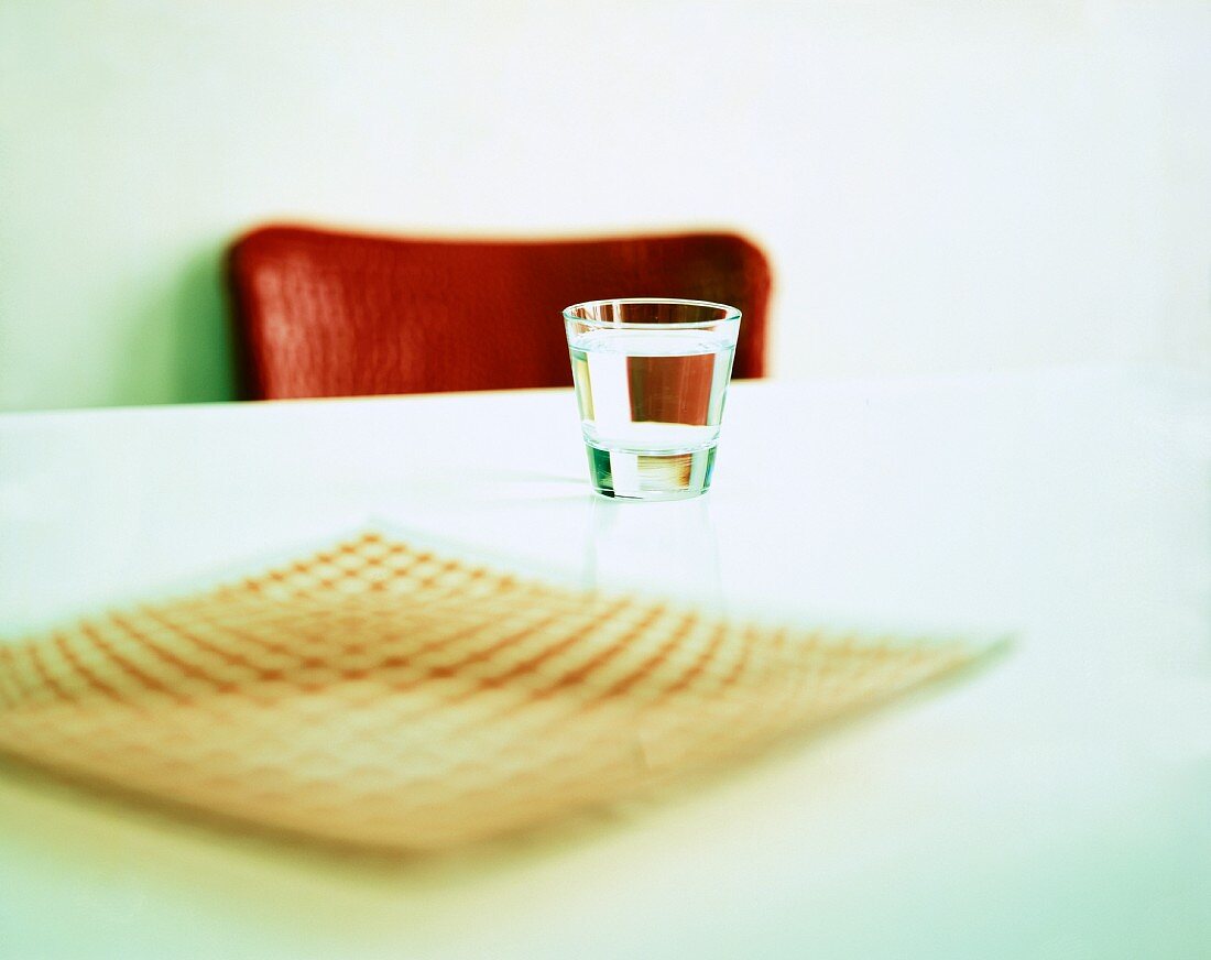 Ein Glas Wasser und ein Teller auf einem Tisch