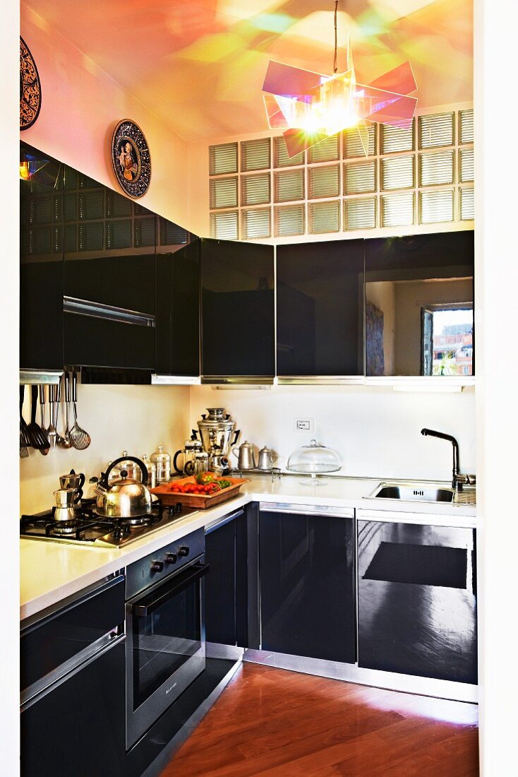 Glossy black kitchen with transom window of glass bricks and contemporary designer lamp