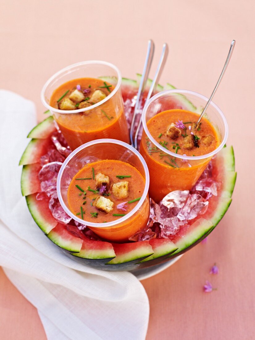 Drei Becher Gazpacho auf einer Wassermelone