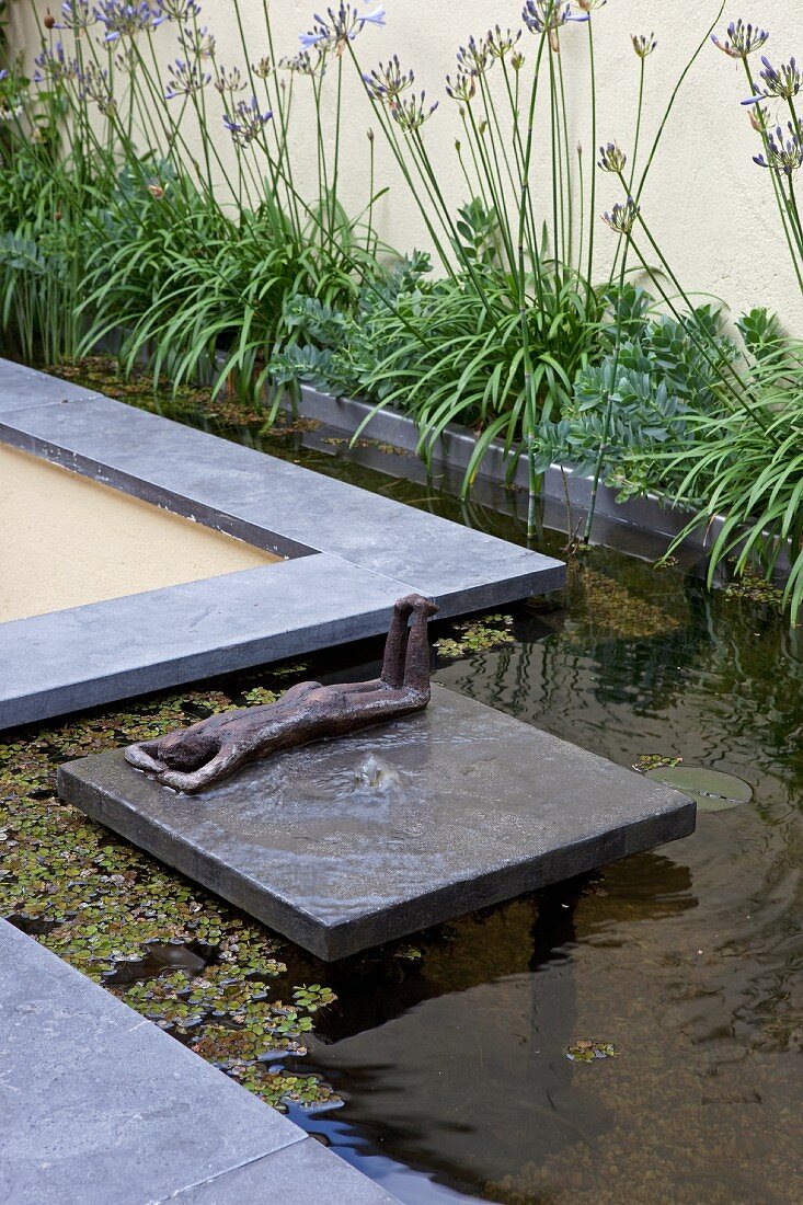 Reclining bronze figure on raft in pool