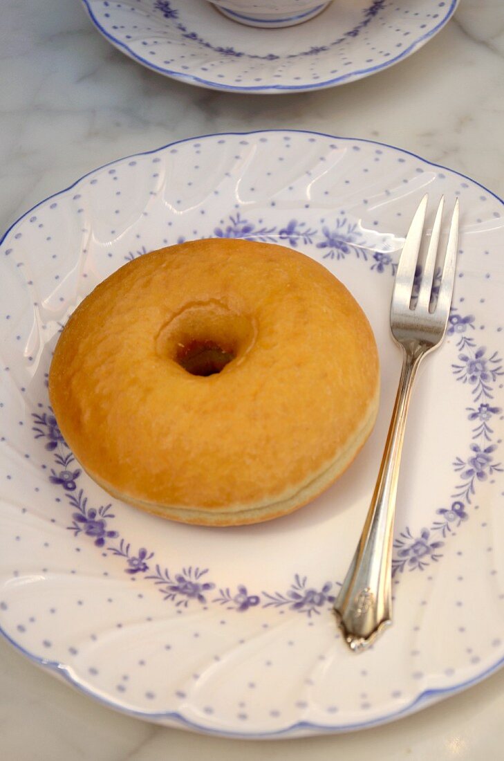 A doughnut and a fork on a plate