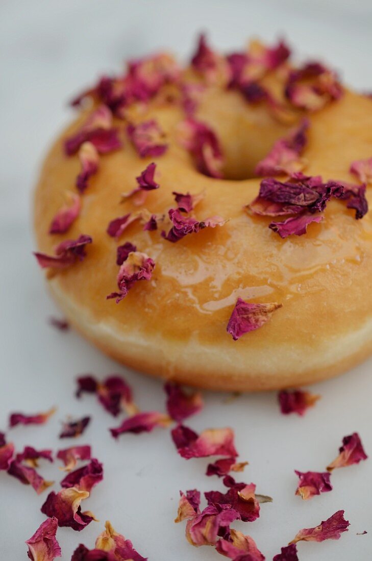 A doughnut decorated with dried rose petals