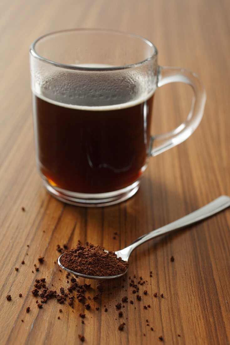 A cup of instant coffee and a spoonful of instant coffee powder