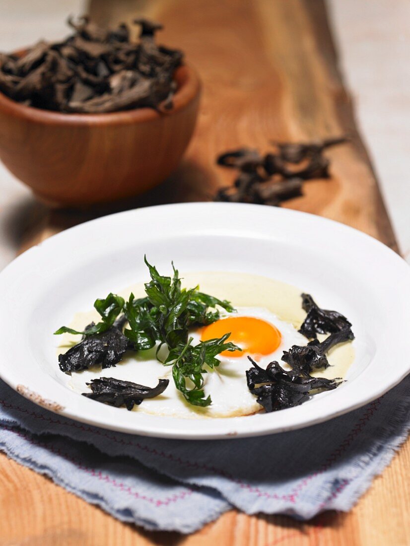 A fried egg with black chanterelles