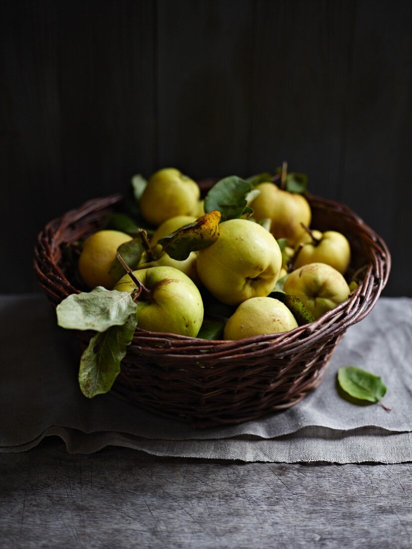 Fresh quinces with leaves in a basket