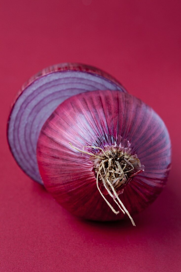 Eine halbierte rote Zwiebel vor rotem Hintergrund