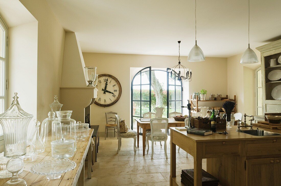 Oversized clock hangs near chimney breast of Provence country house kitchen