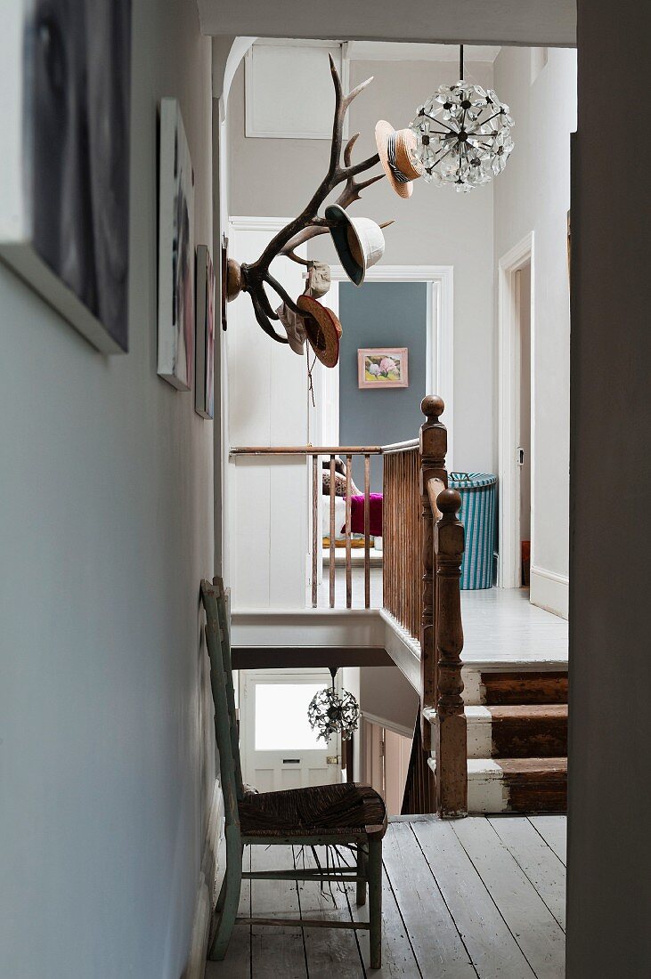Mounted antlers double up as a hat rack on the wall of a landing with wooden balustrade