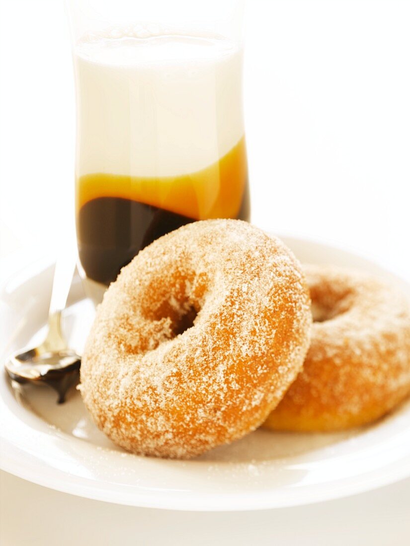 Two Sugared Donuts on a Plate; Glass of Flavored Milk