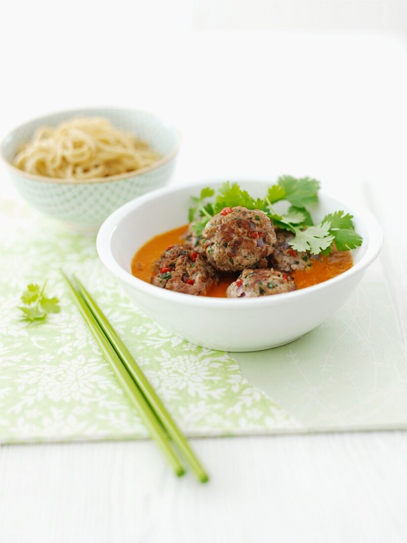 Meatballs in a sauce with coriander and oriental noodles