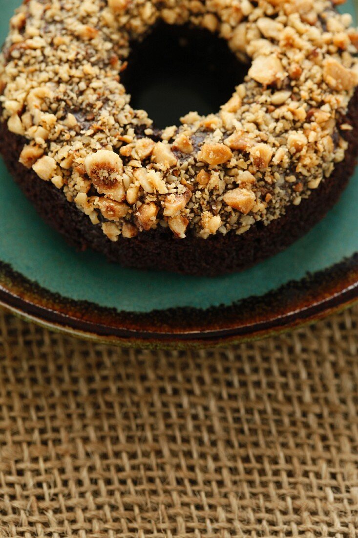 A chocolate and banana doughnut topped with nuts