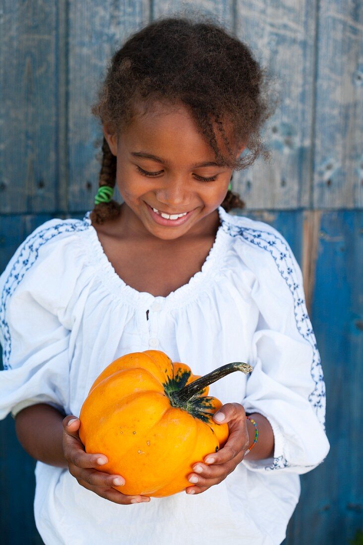 A little girl holding a pumpkin