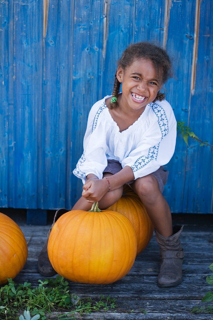 A little girl sitting on a big pumpkin