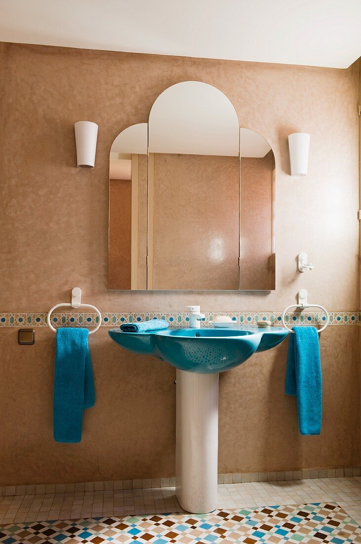 Blue sink in bathroom with zellige floor tiles and blue hand towels