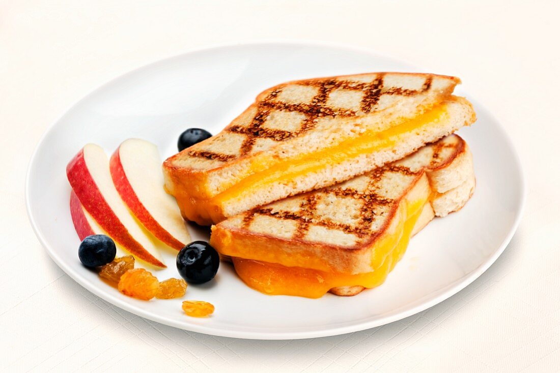 Halved Grill Cheese Sandwich on a White Plate with Fruit