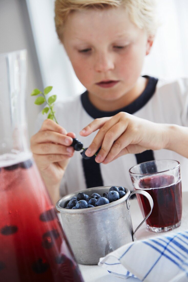 Junge mit Heidelbeersaft und frischen Heidelbeeren