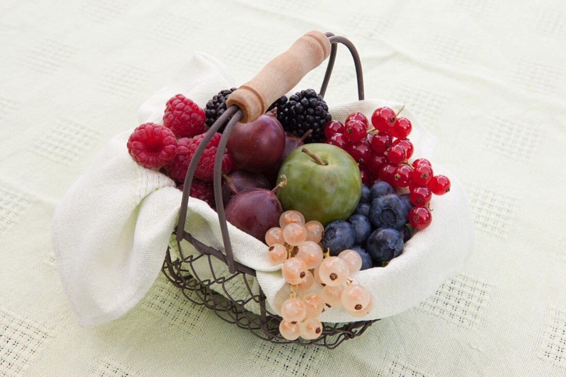 A basket of fruit with berries and greengages